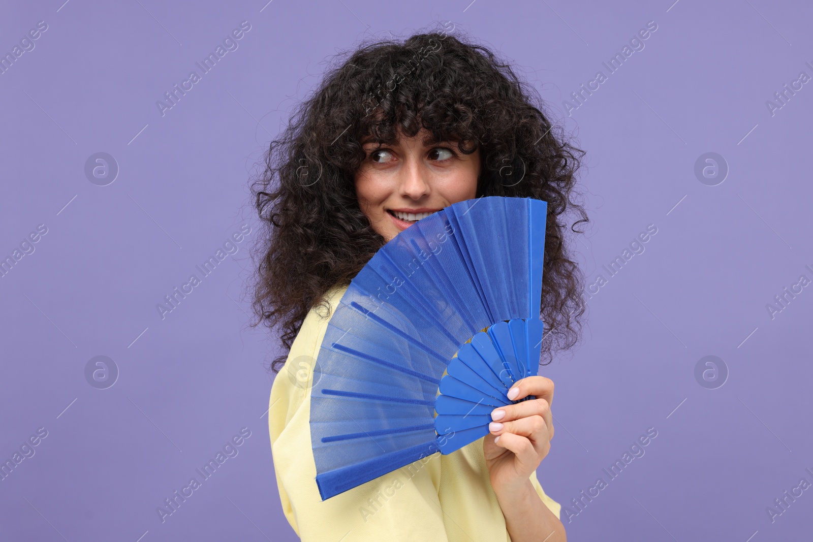 Photo of Happy woman holding hand fan on purple background