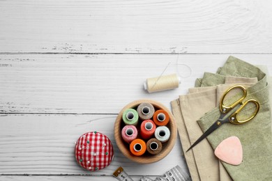 Photo of Flat lay composition with spools of threads and sewing tools on white wooden table, space for text