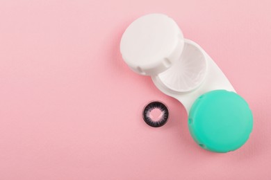 Case with color contact lenses on pink background, top view. Space for text