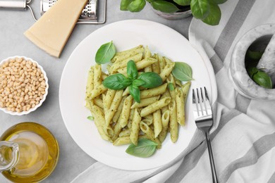 Photo of Delicious pasta with pesto sauce and basil on light grey table, flat lay