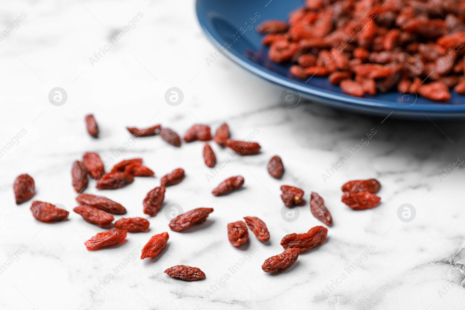 Photo of Dried goji berries on white marble table, closeup