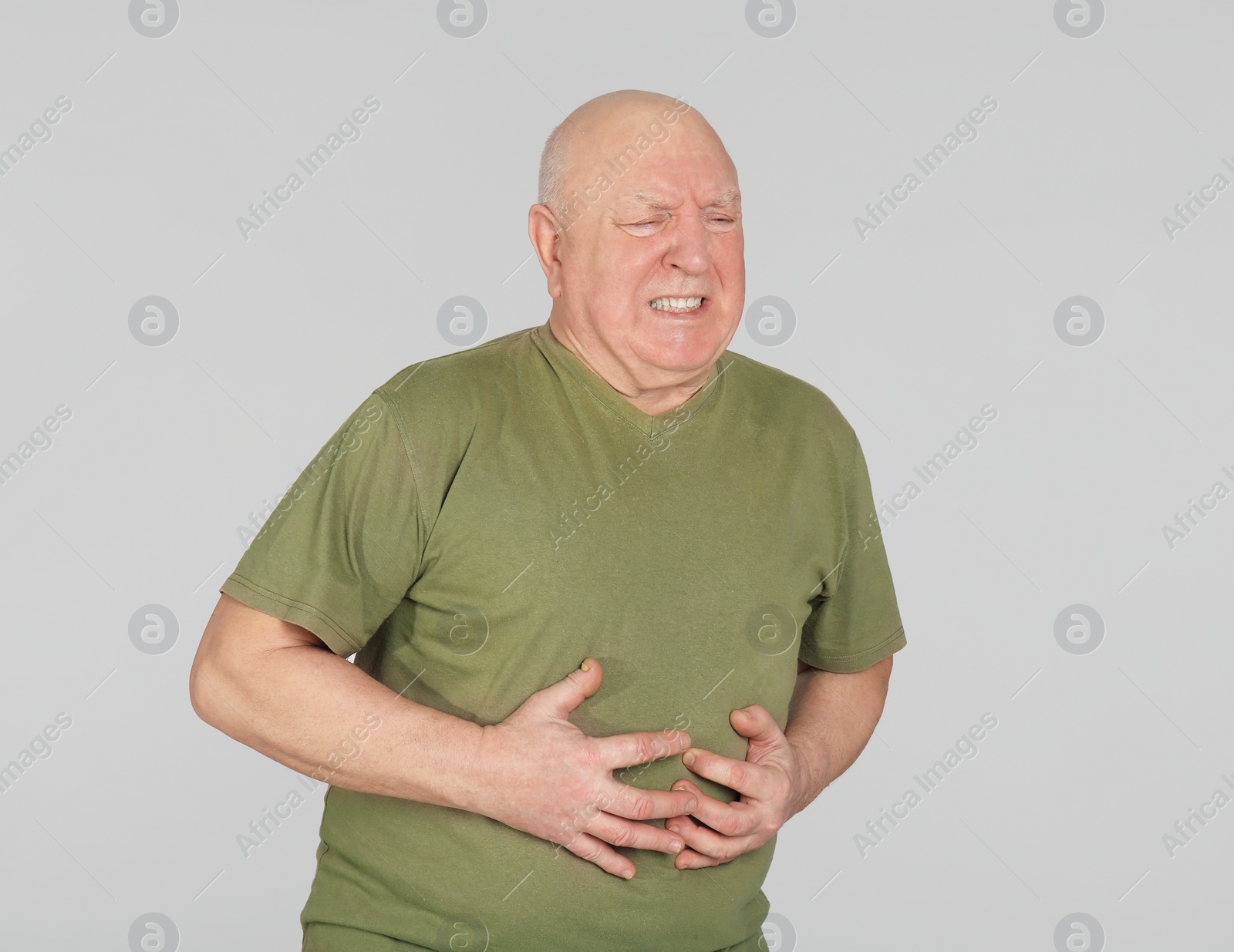 Photo of Senior man suffering from pain in stomach on light background
