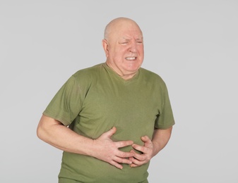Photo of Senior man suffering from pain in stomach on light background