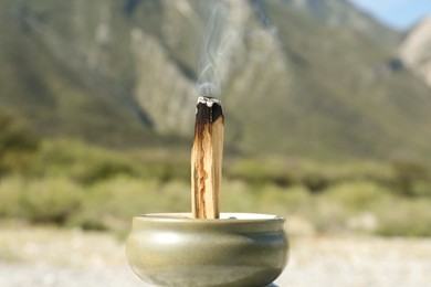 Burning palo santo stick in high mountains, closeup