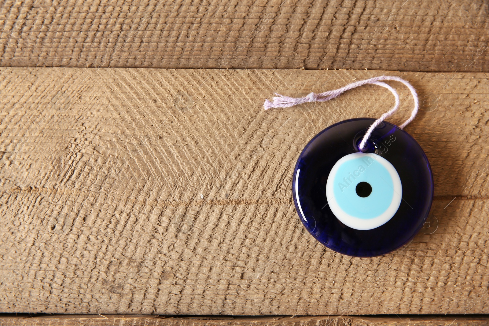 Photo of Evil eye amulet on wooden table, top view. Space for text