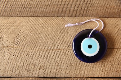 Evil eye amulet on wooden table, top view. Space for text