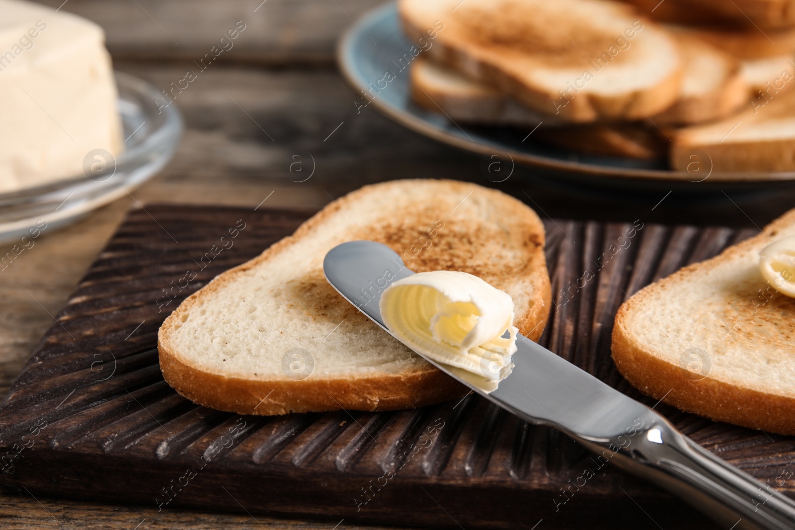 Photo of Toasted bread and knife with butter on wooden board