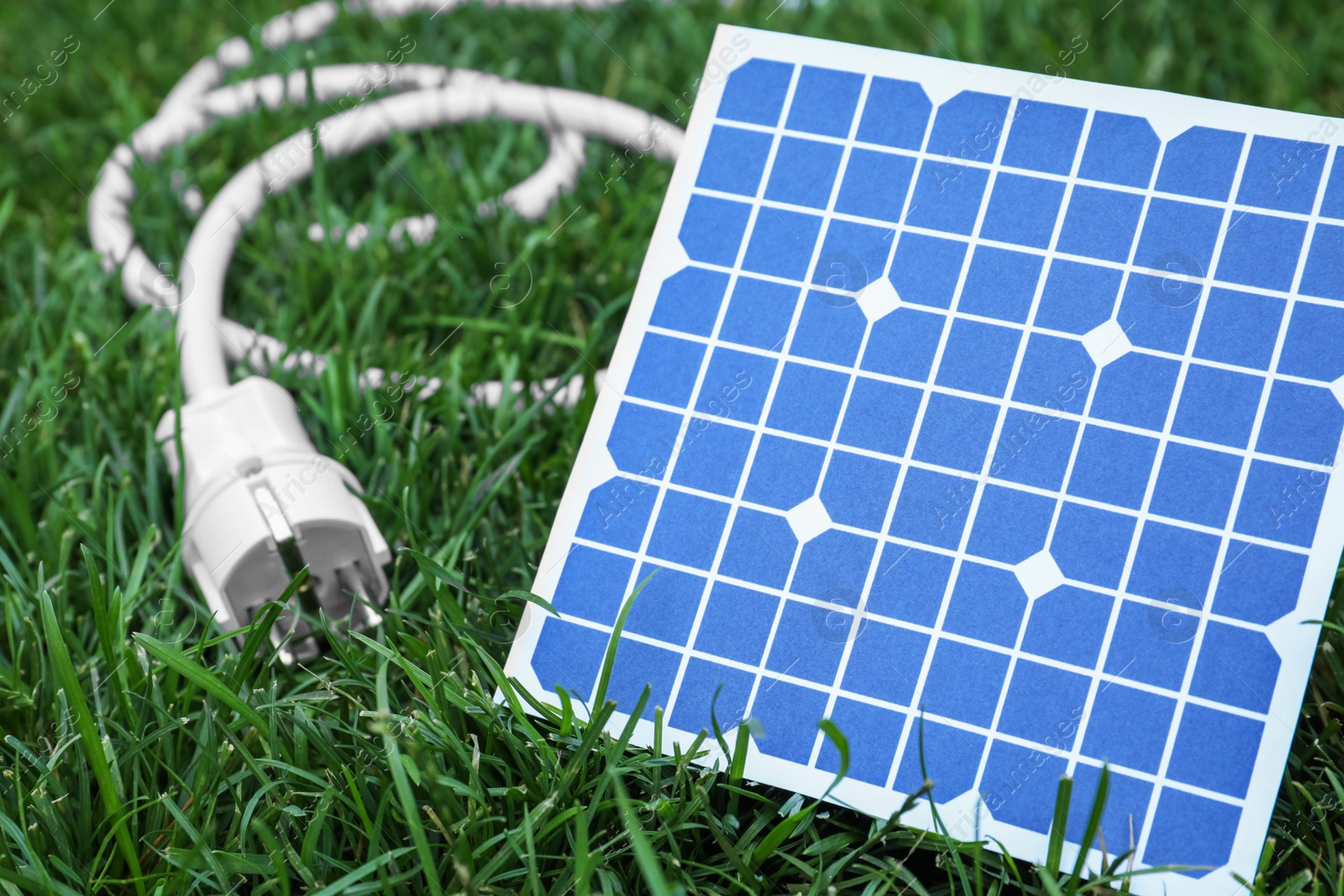 Photo of Solar panel and plug on green grass, closeup