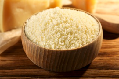 Photo of Bowl with grated parmesan cheese on wooden table, closeup