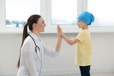 Photo of Childhood cancer. Doctor and little patient giving high five in hospital