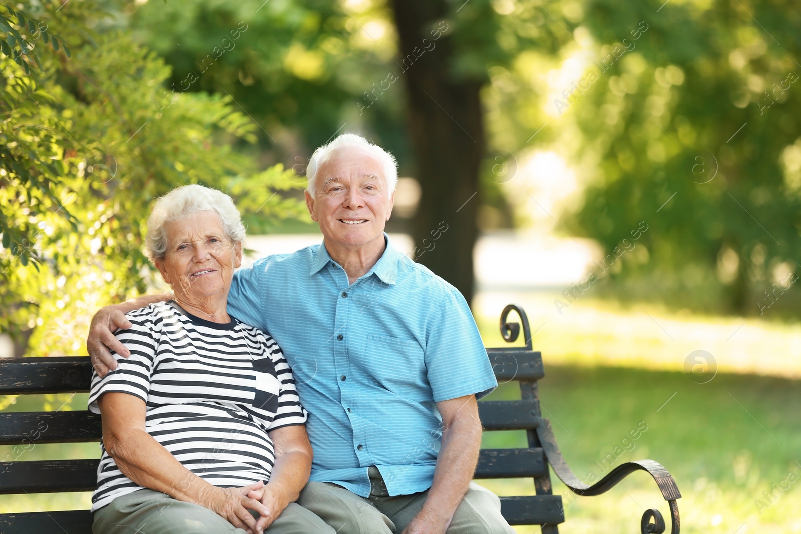 Photo of Elderly couple resting on bench in park