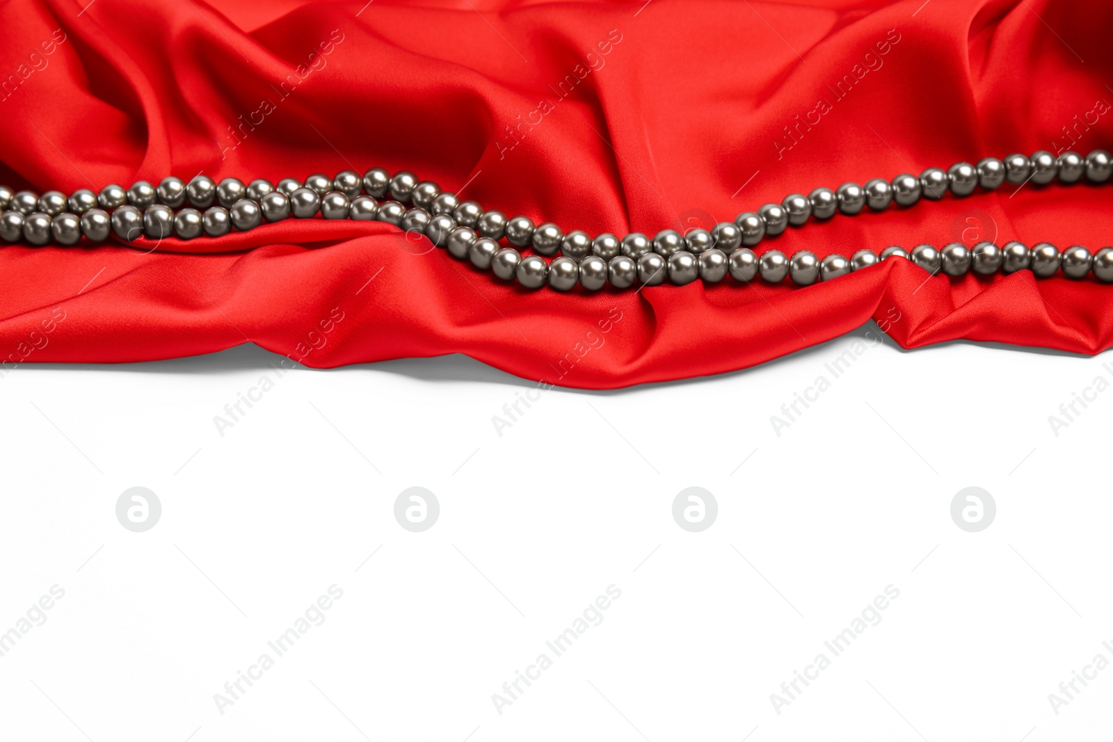 Photo of Beautiful pearls and red silk on white background