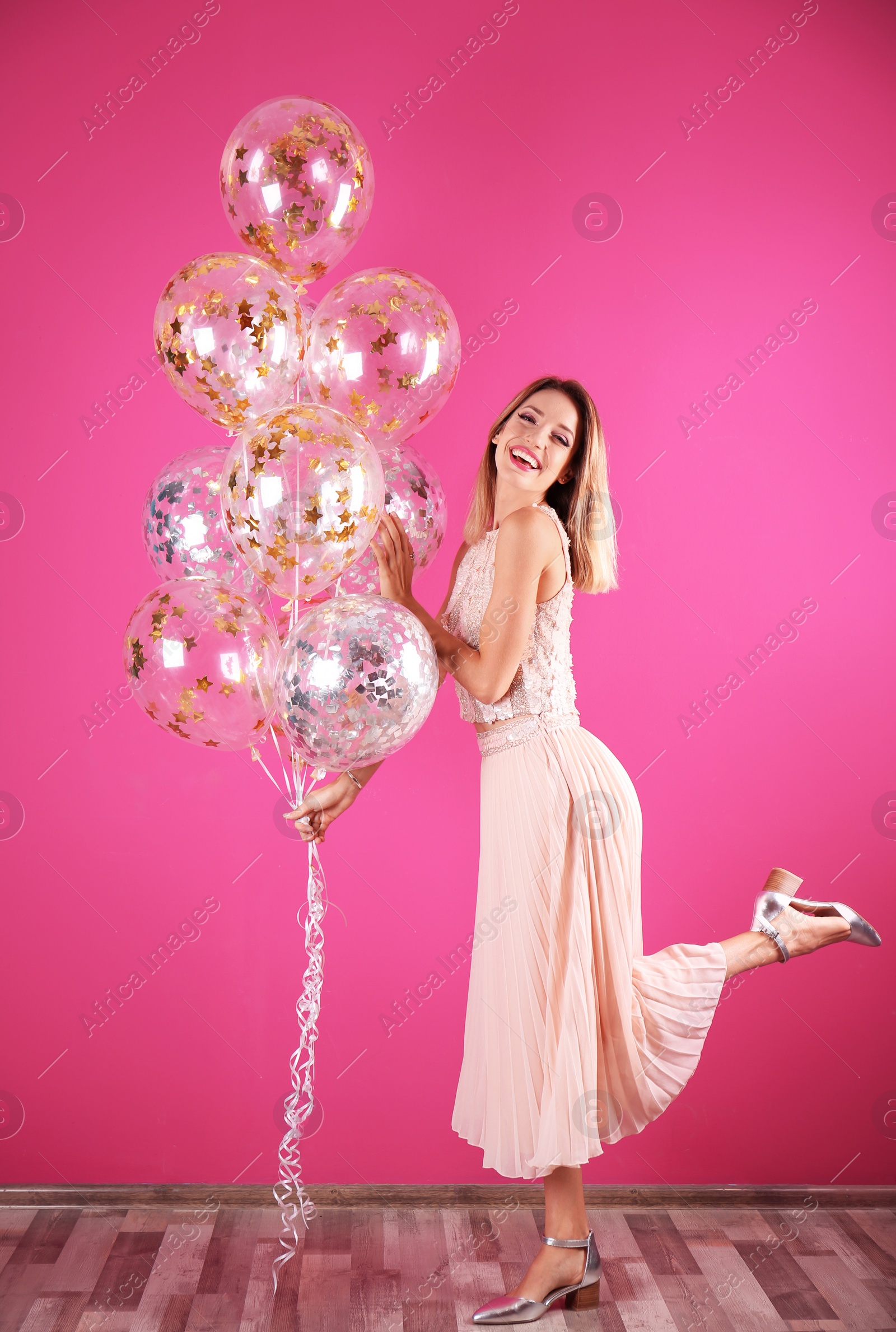 Photo of Young woman with air balloons near color wall