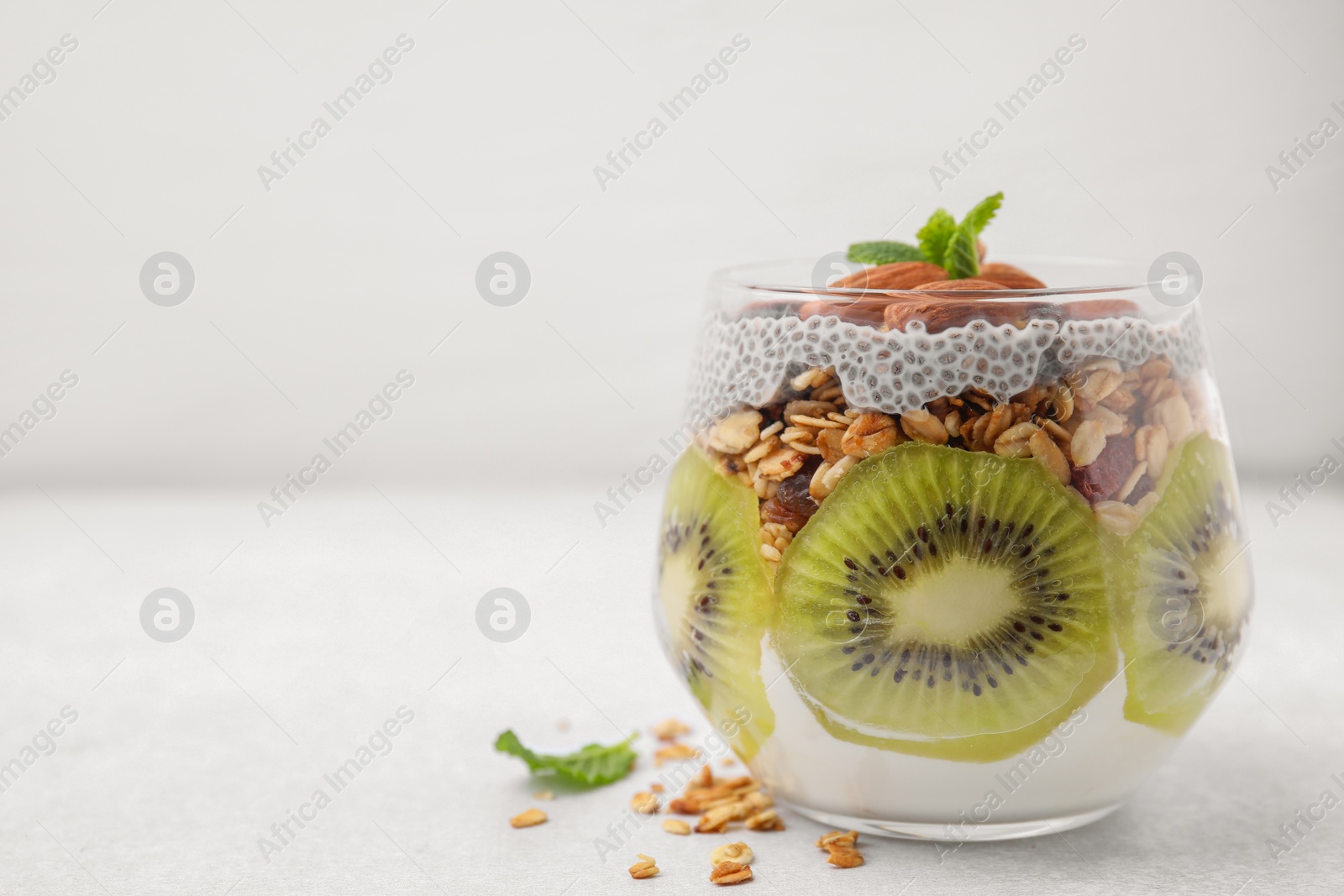 Photo of Delicious dessert with kiwi, chia seeds and almonds on white table, space for text