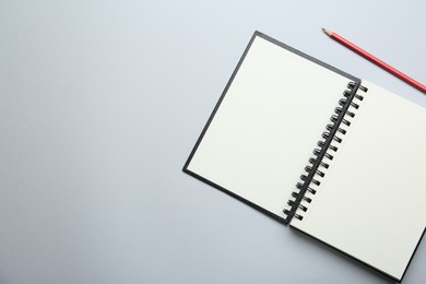 Photo of One notebook and pencil on light grey background, top view. Space for text