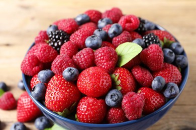 Photo of Different fresh ripe berries in bowl on table, closeup