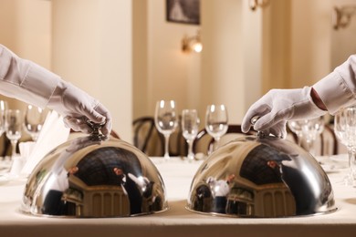 Photo of Men setting table in restaurant, closeup. Professional butler courses