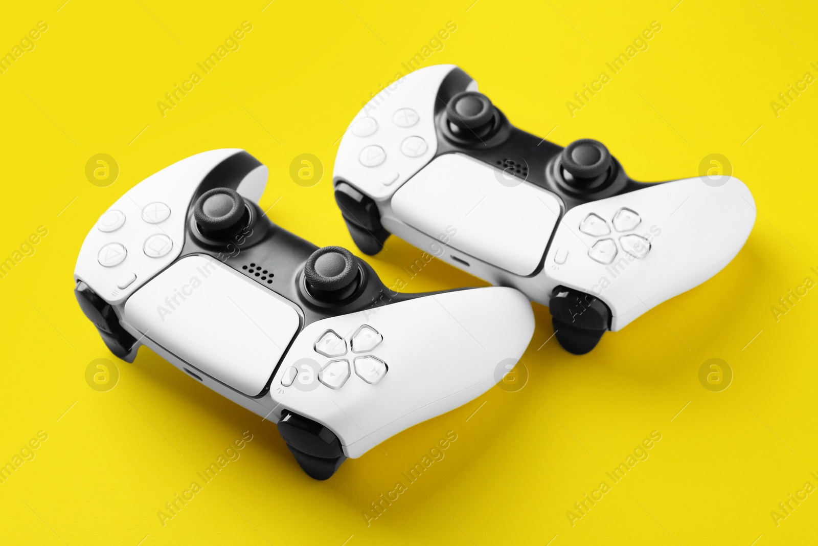 Photo of Two wireless game controllers on yellow background