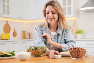 Woman at wooden table with healthy food in kitchen. Keto diet