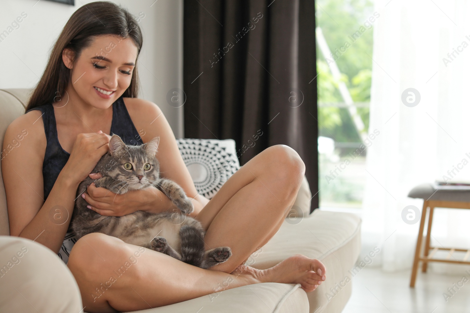 Photo of Young woman with cute cat at home, space for text. Pet and owner