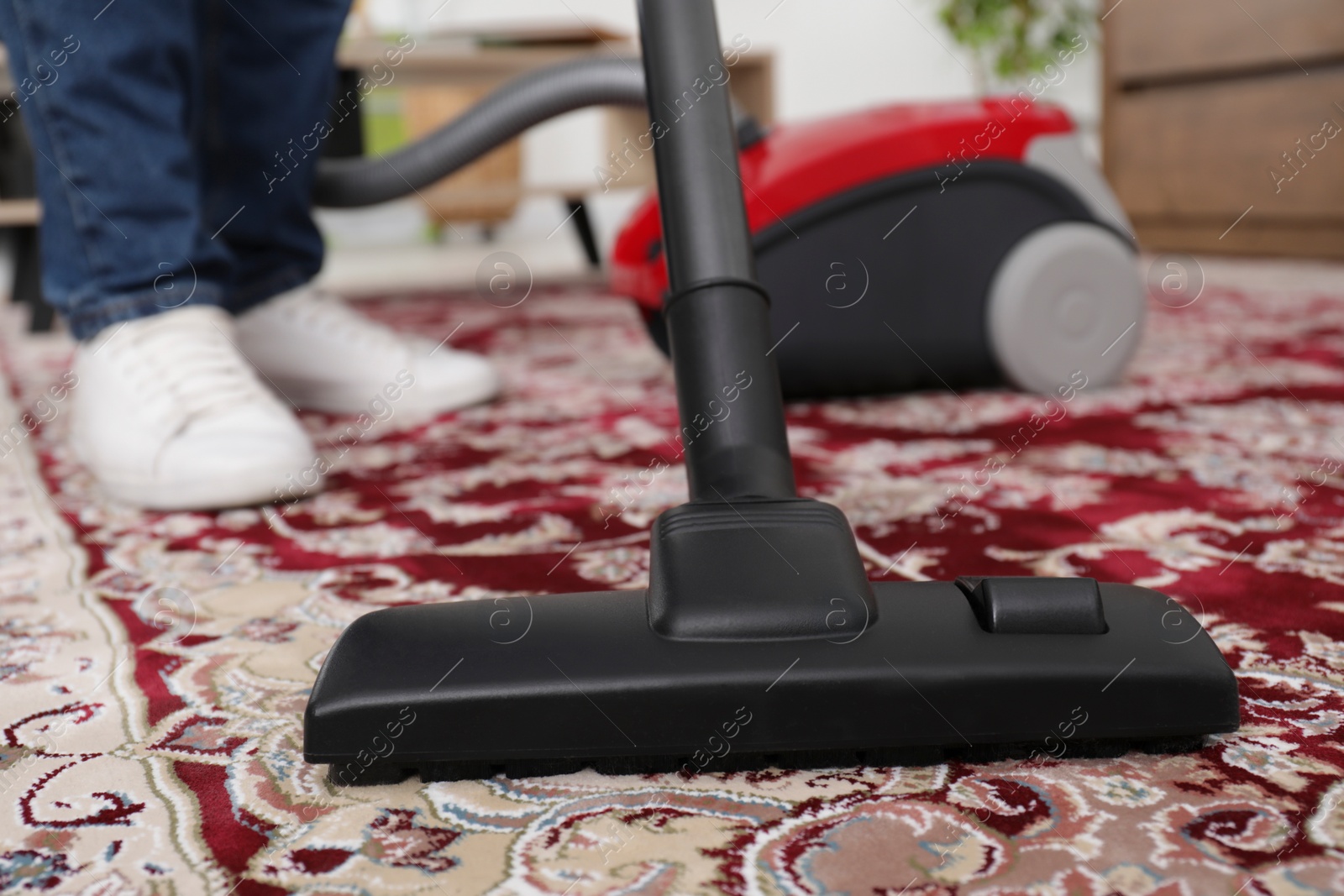 Photo of Man cleaning carpet with vacuum cleaner at home, closeup