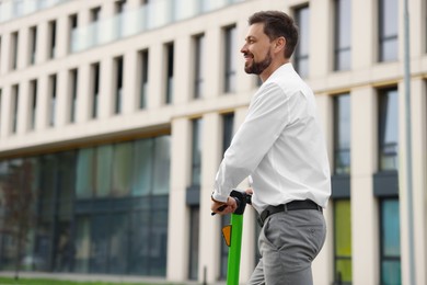 Businessman with modern kick scooter on city street, space for text