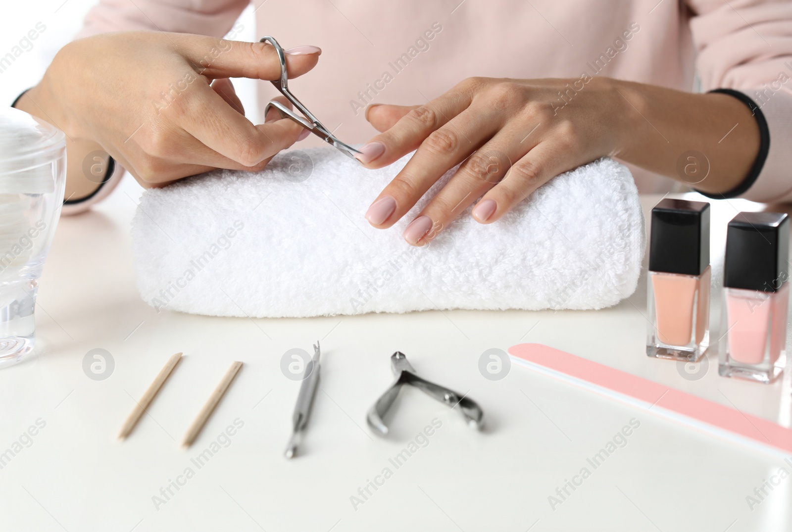 Photo of Woman cutting nails at table, closeup. At-home manicure