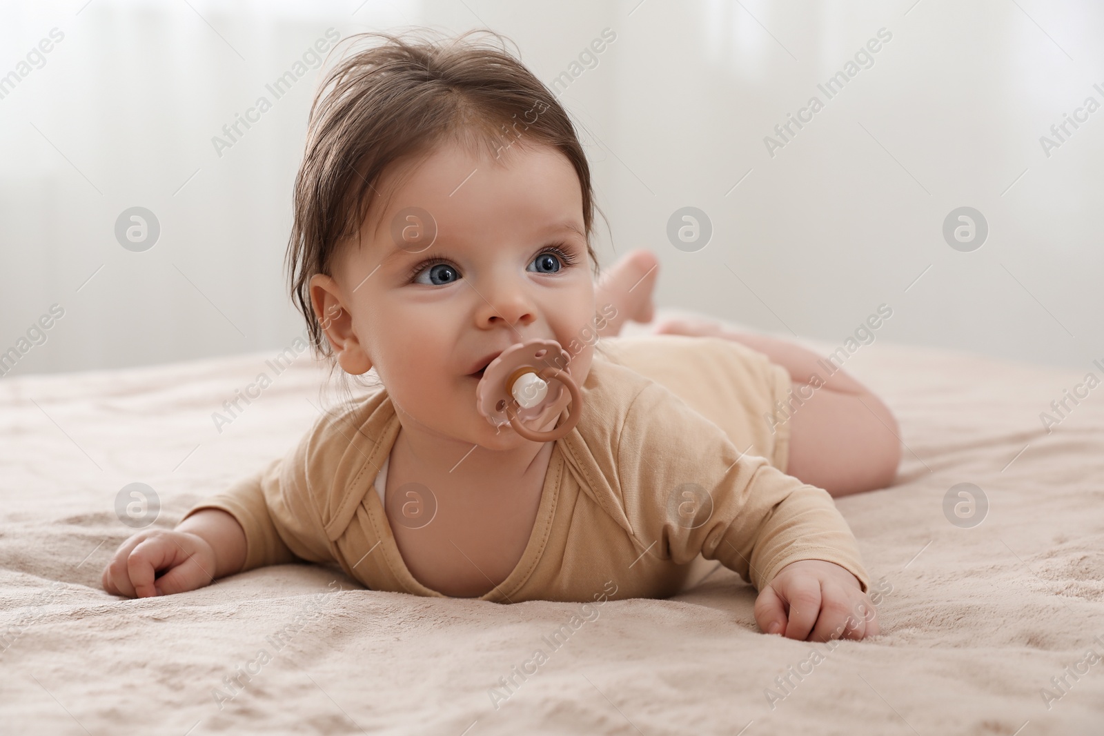 Photo of Cute little baby with pacifier on bed indoors