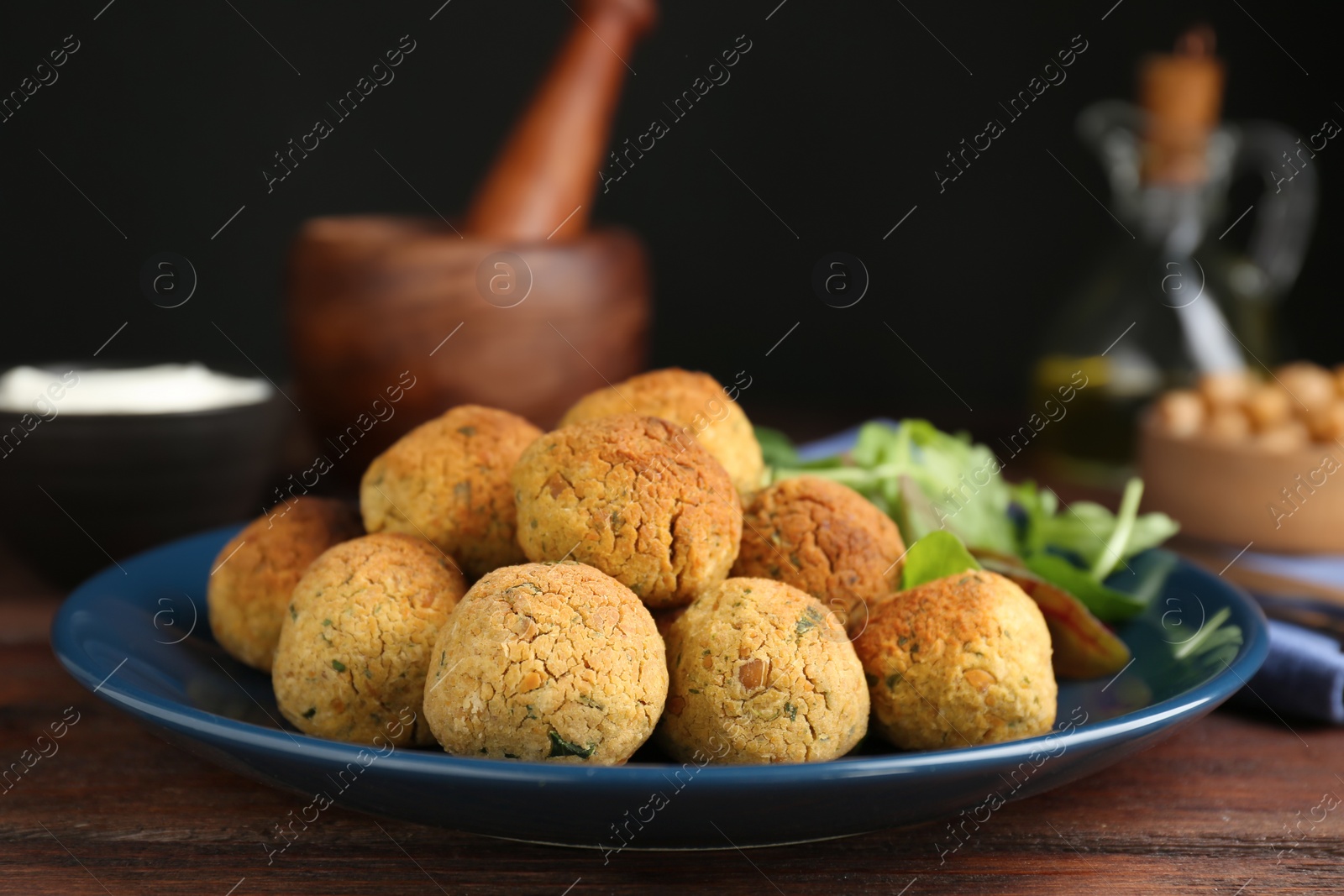 Photo of Delicious falafel balls with herbs on wooden table, closeup