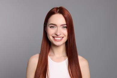 Photo of Happy woman with red dyed hair on light gray background