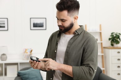 Photo of Diabetes test. Man using glucometer at home