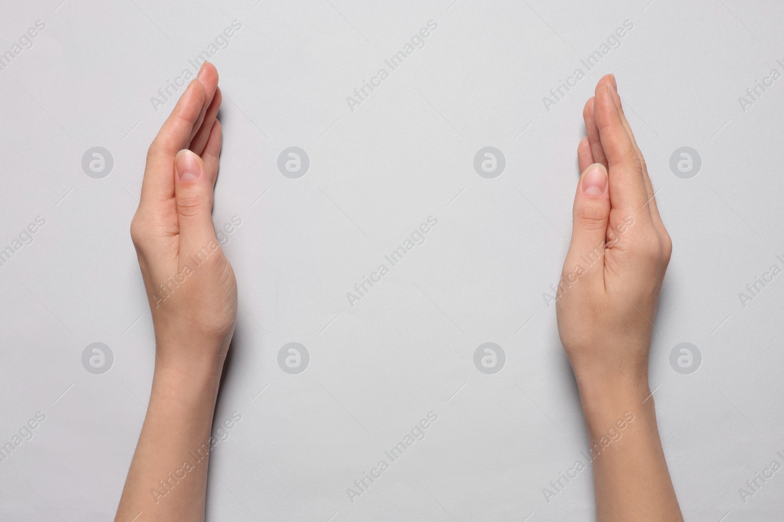 Photo of Woman holding on light grey background, closeup of hands. Space for text