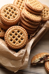 Photo of Tasty sandwich cookies with cream on wooden table, above view