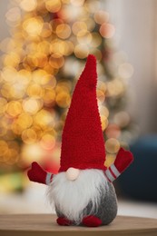 Photo of Cute Christmas gnome on wooden table in decorated room