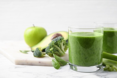 Delicious fresh green juice on white marble table. Space for text