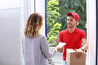 Photo of Woman paying courier for delivered parcel on doorstep
