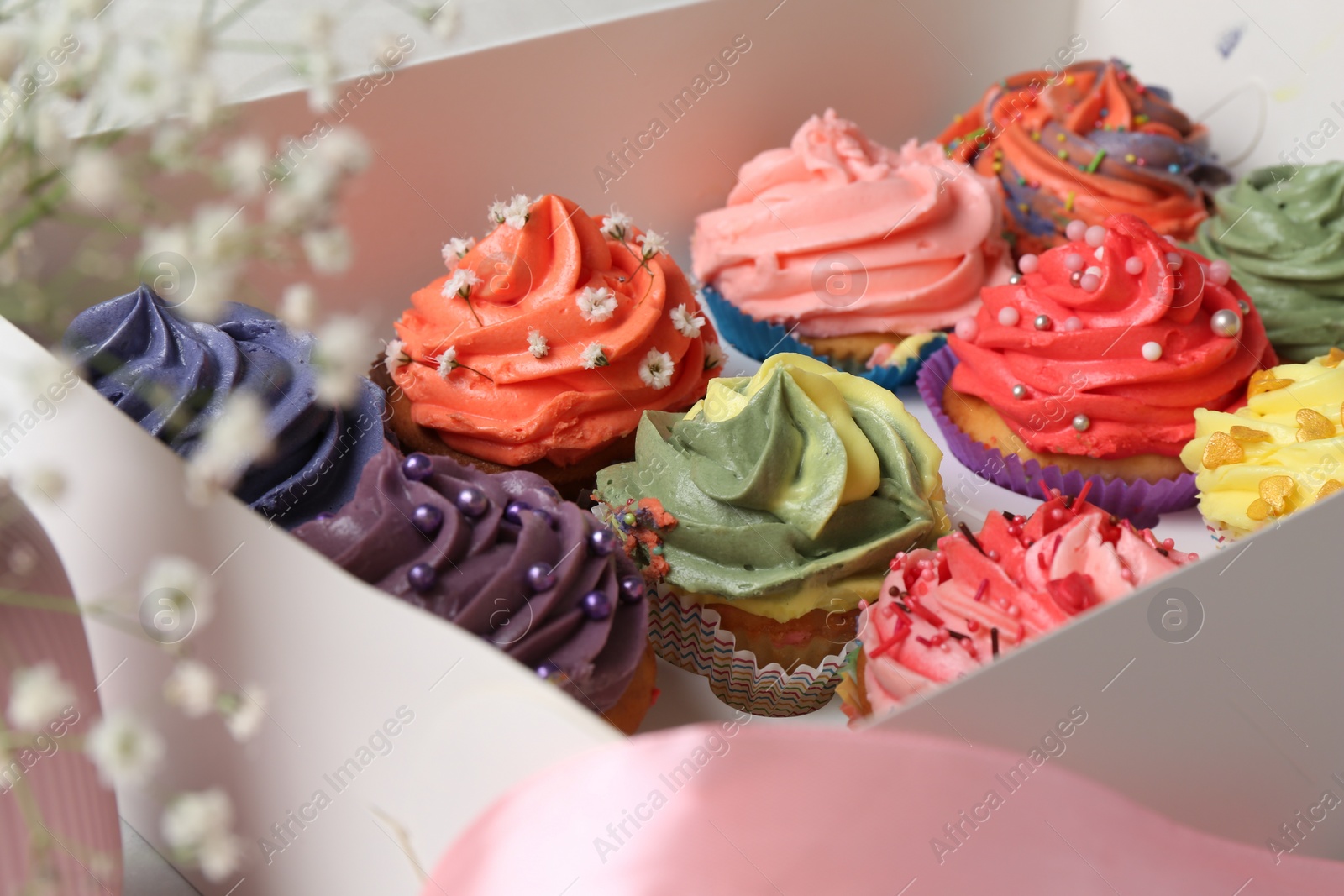 Photo of Different colorful cupcakes in box, closeup view