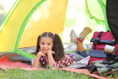 Little girl resting in tent outdoors. Summer camp