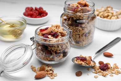 Jars of tasty granola with nuts and dry fruits on white marble table