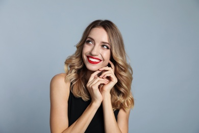 Photo of Happy young woman on grey background. Christmas celebration