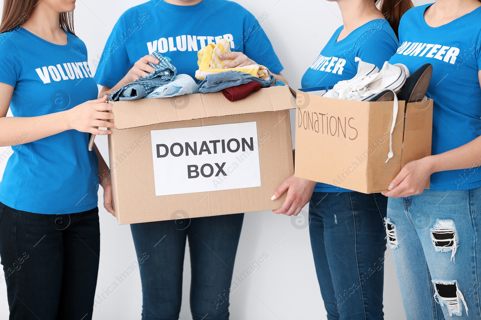 Photo of Team of volunteers with donation boxes on light background