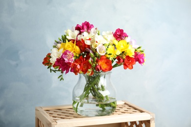 Bouquet of spring freesia flowers in vase on color background