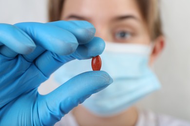 Photo of Doctor holding red pill, focus on drug. Anemia concept
