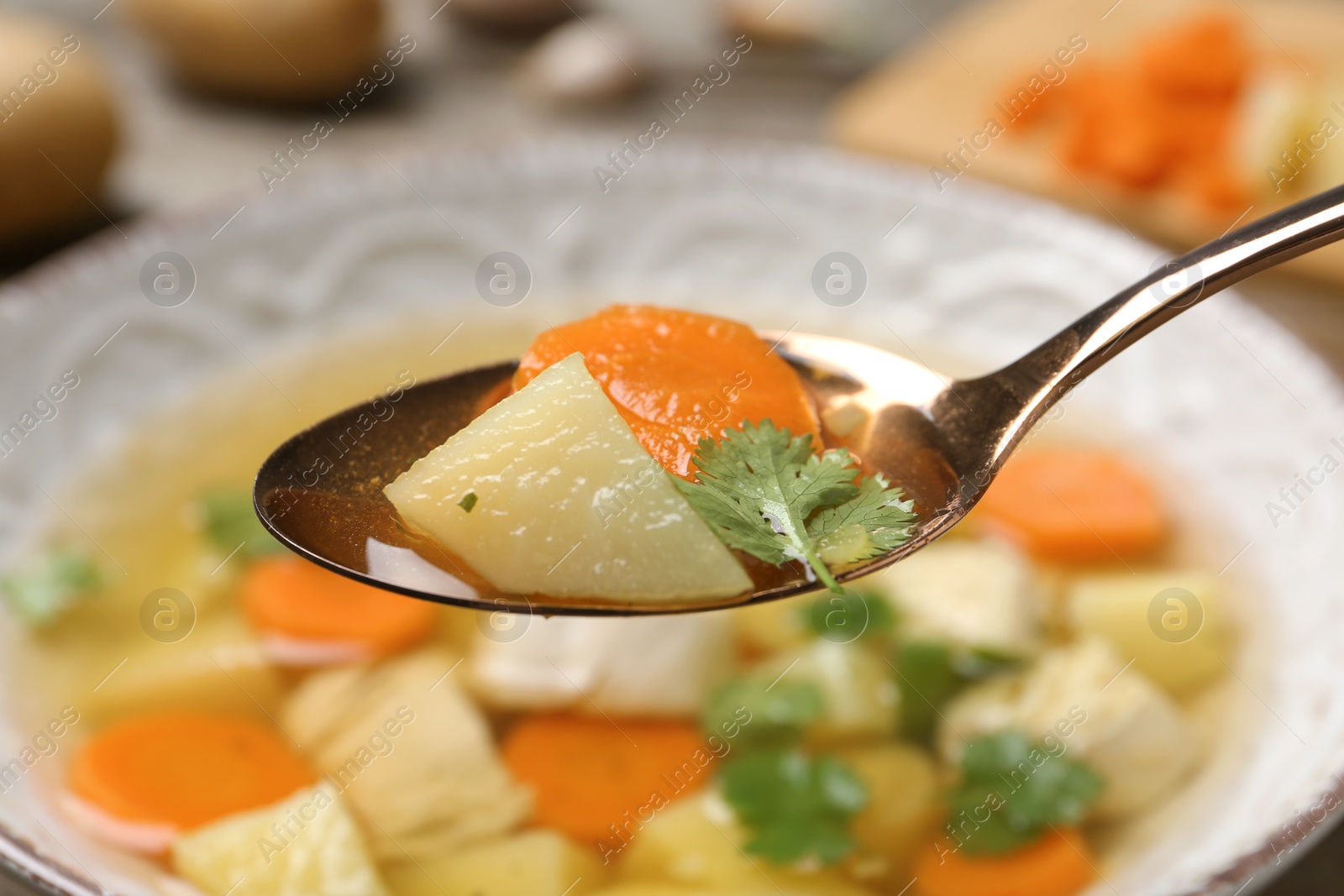 Photo of Spoon with fresh homemade chicken soup on blurred background, closeup