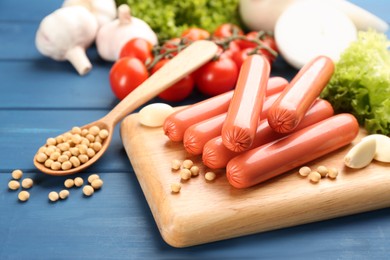 Photo of Fresh raw vegetarian sausages, soybeans and vegetables on blue wooden table
