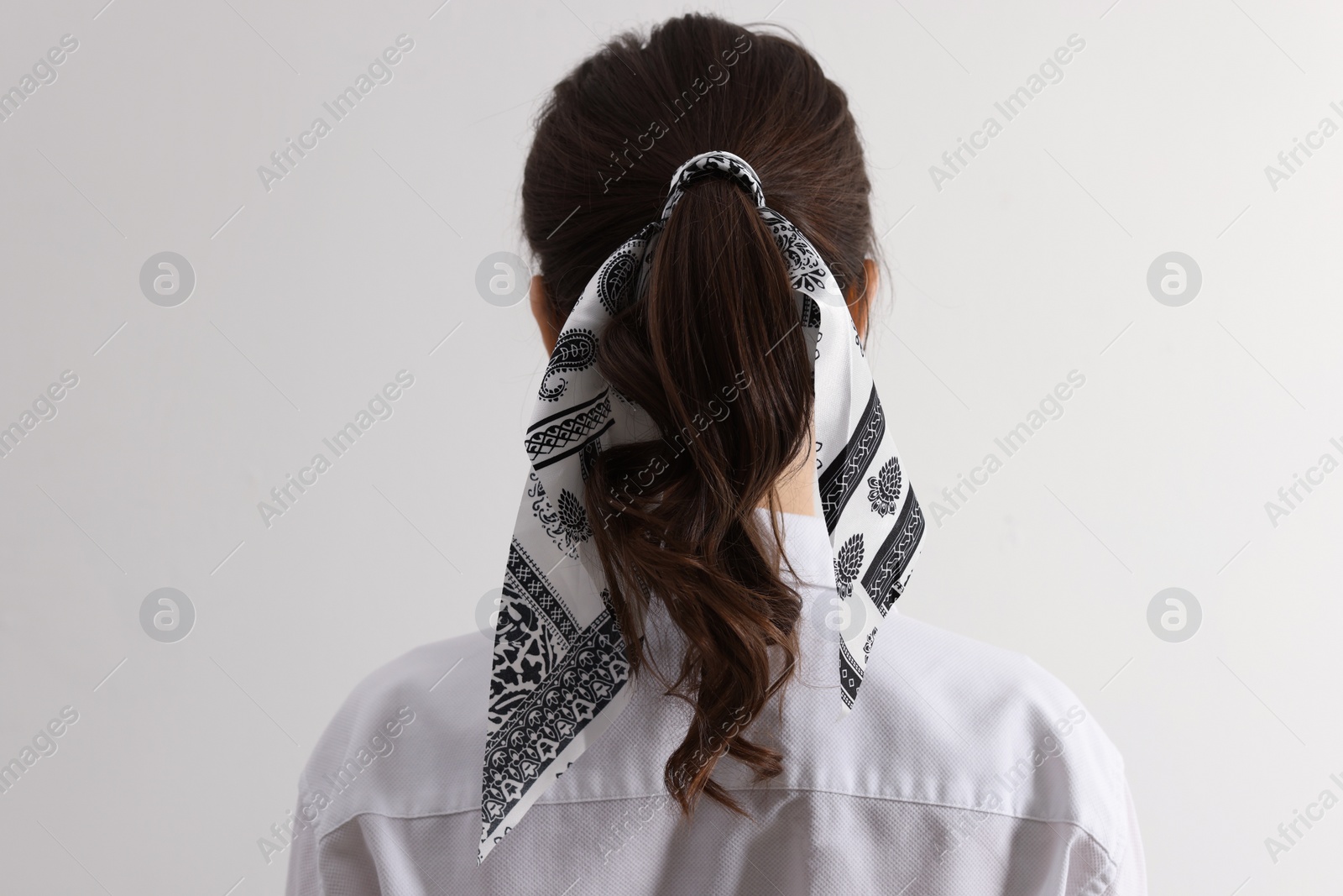 Photo of Young woman with stylish bandana on light background, back view