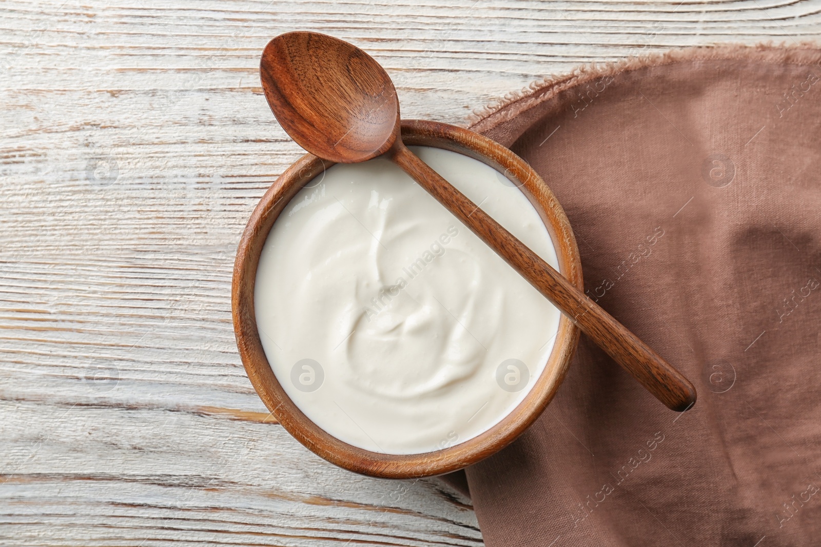 Photo of Bowl with tasty yogurt on wooden background