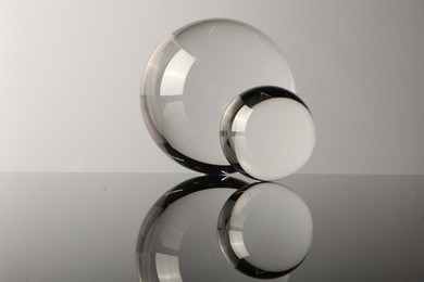 Photo of Transparent glass balls on mirror surface against light background
