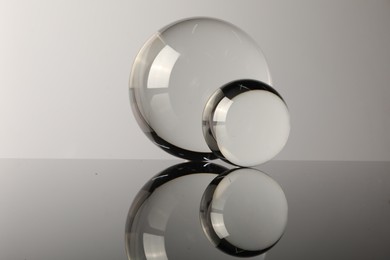 Transparent glass balls on mirror surface against light background