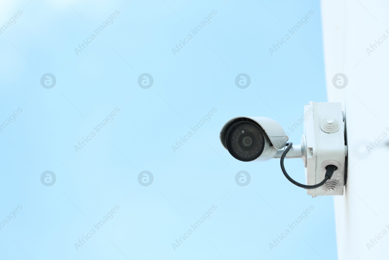 Photo of Modern CCTV security camera on building wall outdoors. Space for text